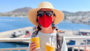 Liane mit Sommerhut, Sonnenbrille und roter Gesichtsmaske.